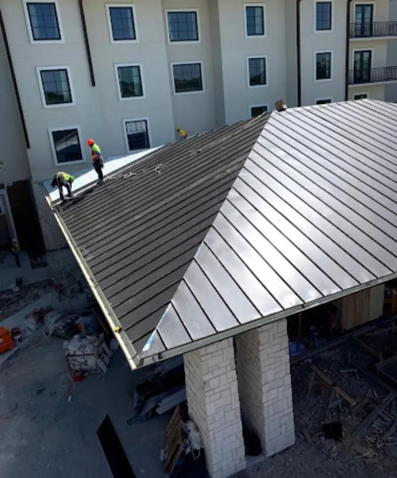 Crew installing standing seam metal roof panels on a commercial project in East Caln